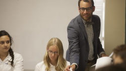A teacher grabs a piece of paper from a desk