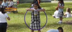 A young lady rips open a plastic bag containing food on the playground