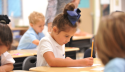 A young student writes onto her paper in class