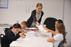 A teacher giving a young student a piece of paper